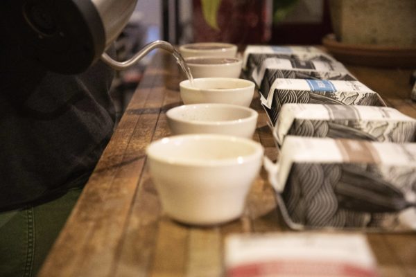 A barista pours hot water into cups for a cupping session.